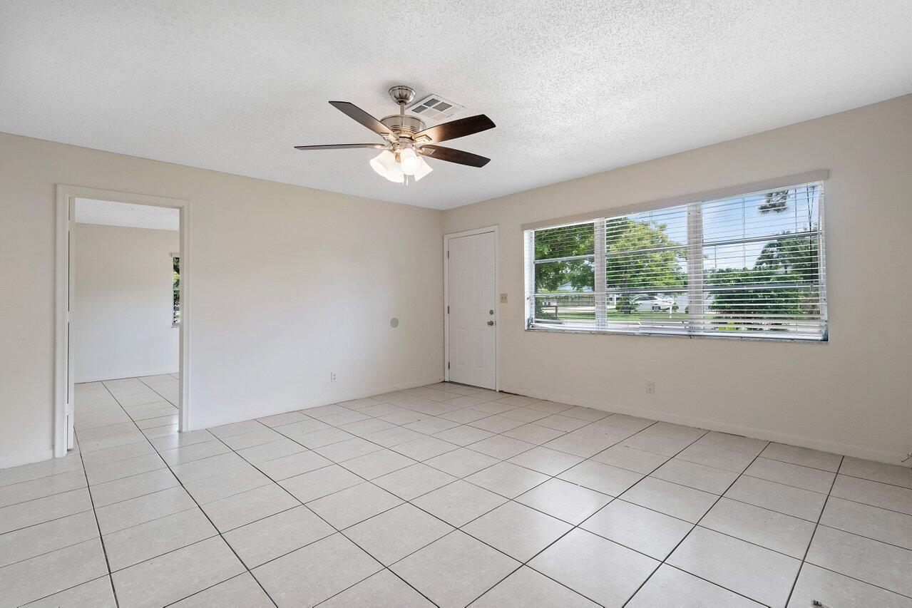 An empty room with light-colored tile flooring, a ceiling fan, and a large window — 5854 Kumquat Road # A, FL 33413, FL
