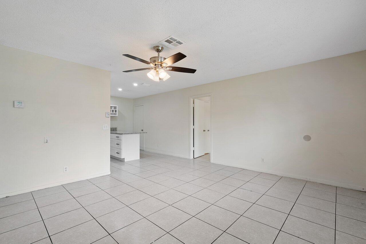 An open-concept living area with light-colored tile flooring, a ceiling fan, and a kitchen island — 5854 Kumquat Road # A, FL 33413, FL