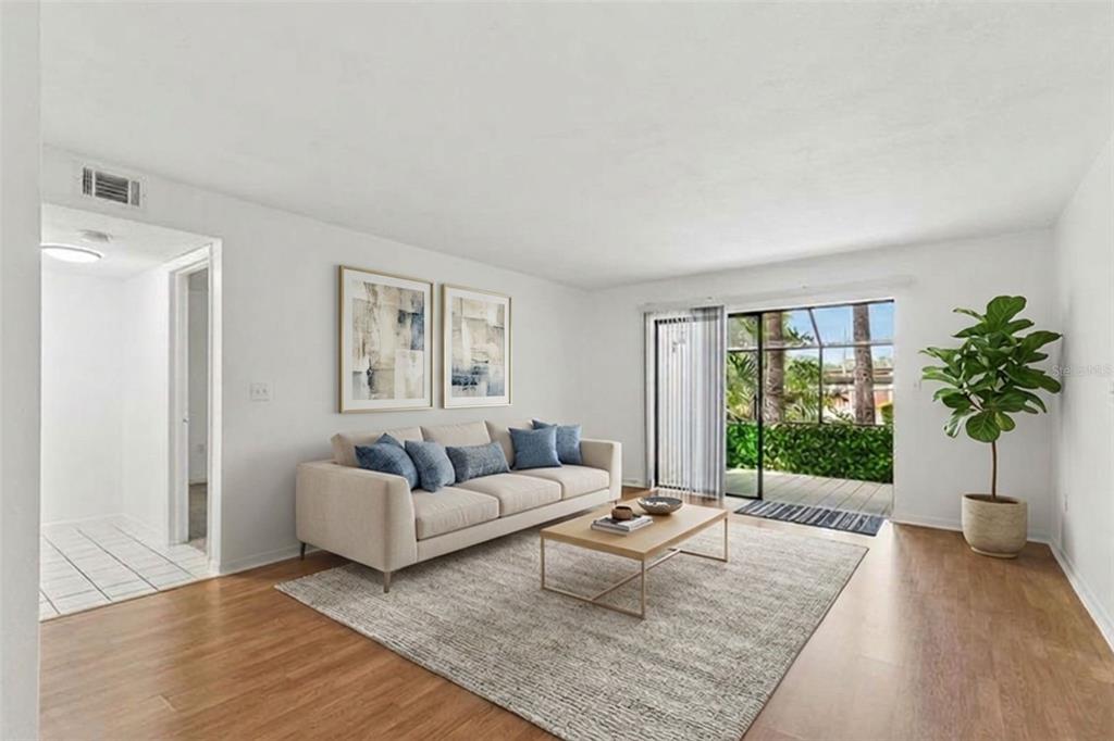 A living room features a beige sofa, a coffee table, and a sliding glass door — 2971 ESTANCIA BOULEVARD UNIT 313, CLEARWATER, FL