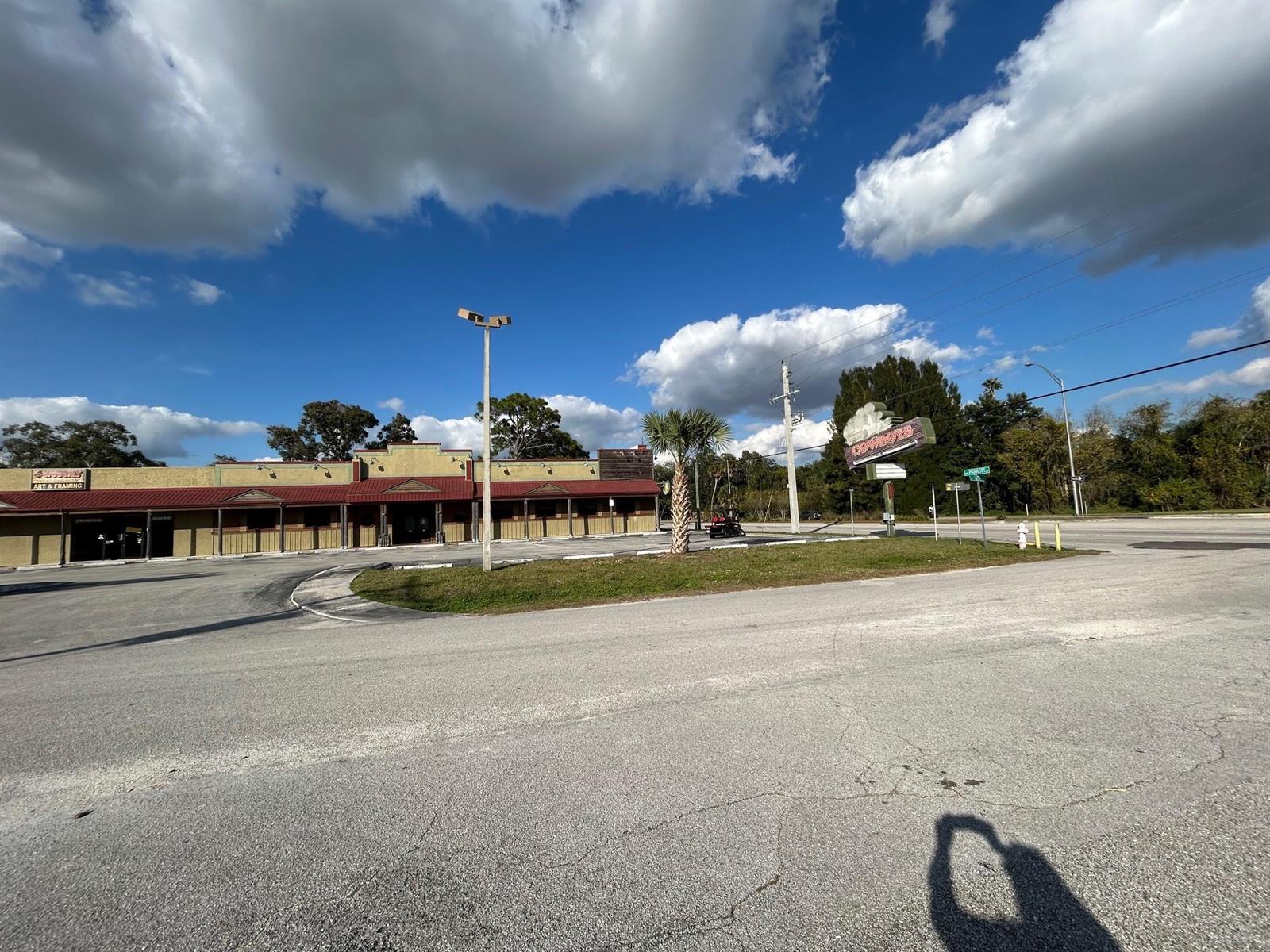 A low-rise commercial building with a red metal roof sits behind a paved parking lot — 102 SW 14th Street, Okeechobee FL 34974, OKEECHOBEE, FL
