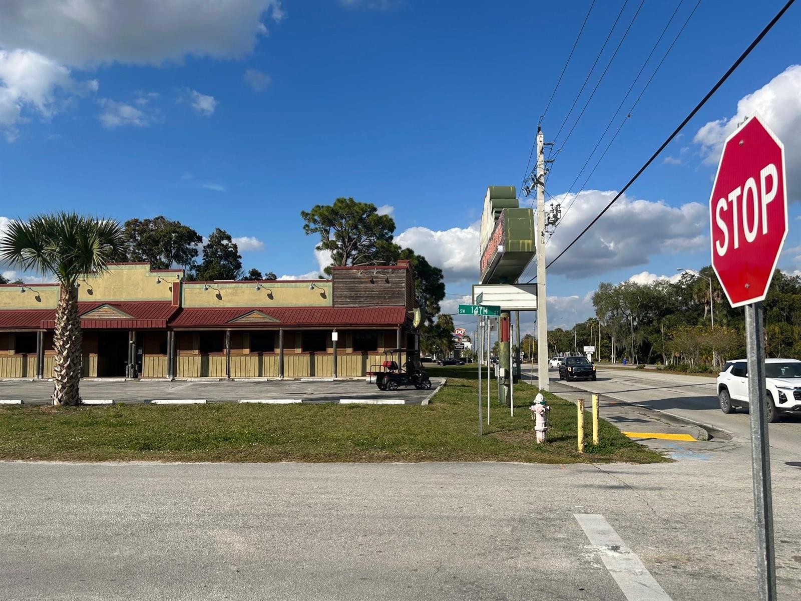 A commercial building with a red metal roof sits next to a stop sign — 102 SW 14th Street, Okeechobee FL 34974, OKEECHOBEE, FL