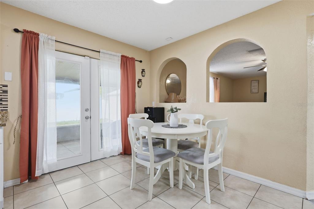A dining area features a white table, four chairs, tile flooring, and arched wall cutouts — 1142 NORMANDY DRIVE, KISSIMMEE, FL