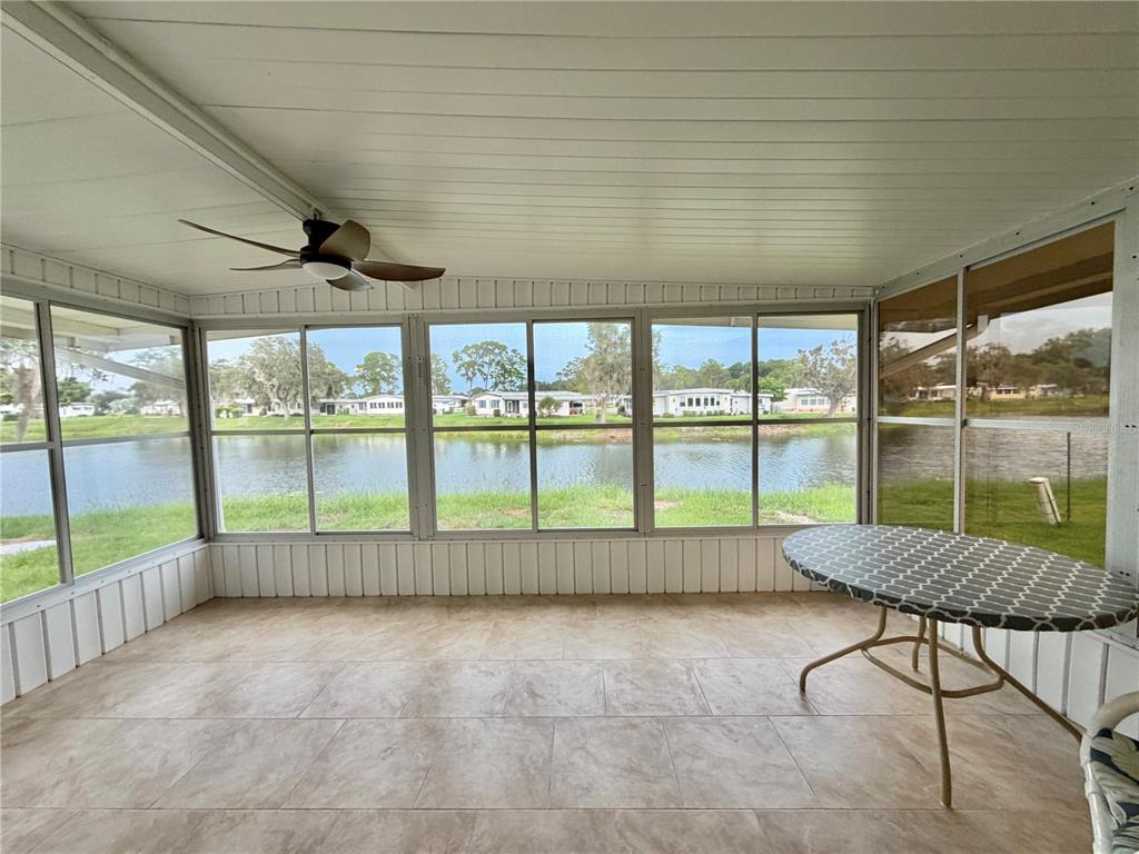 A living room with a striped sofa, wicker chairs, a coffee table, and wood flooring — 119 AUDUBON DRIVE, LEESBURG, FL