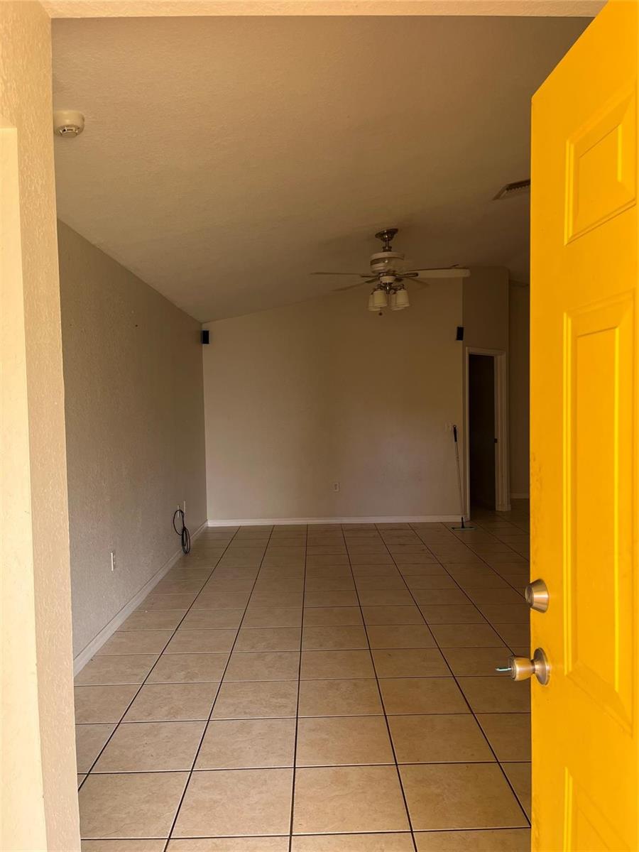 An interior view of a room with light-colored tile flooring and a yellow door — 3049 SE 38th Avenue, Okeechobee FL 34974, OKEECHOBEE, FL