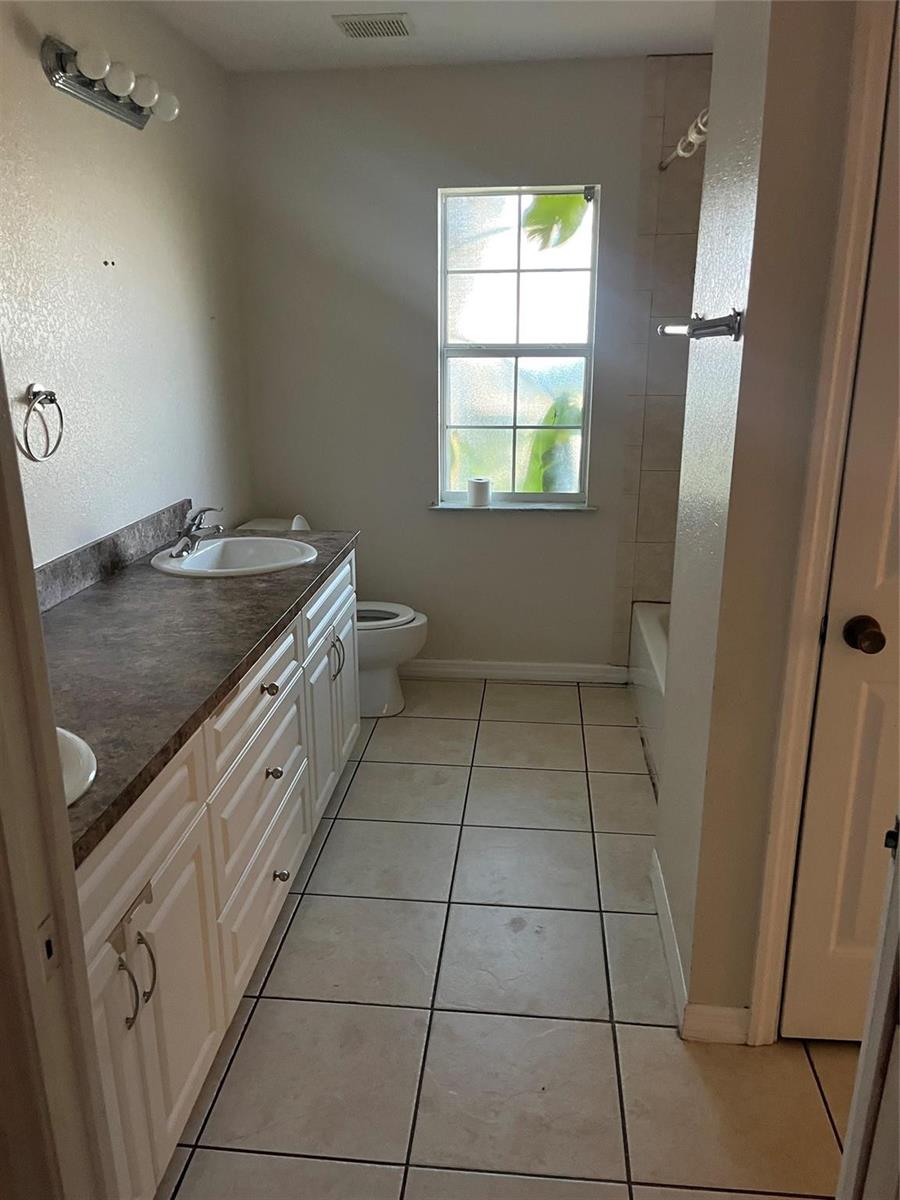 A bathroom features a double vanity with a dark countertop, a toilet, and a tub — 3049 SE 38th Avenue, Okeechobee FL 34974, OKEECHOBEE, FL