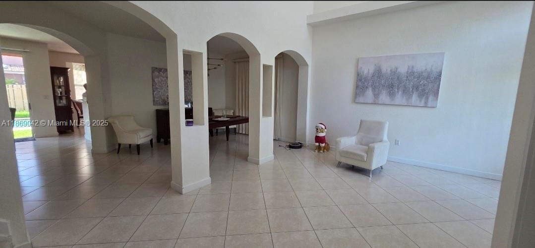 An open-concept living and dining area features white walls, tiled floors, and arched architectural openings — 16448 SW 67th Ter, Miami FL 33193, MIAMI, FL
