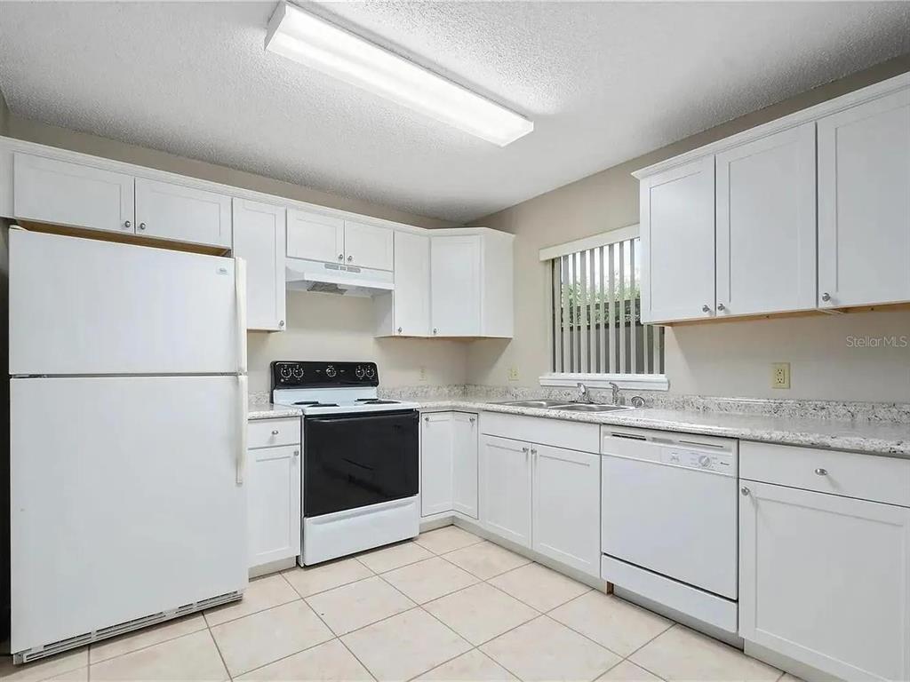 A kitchen with white cabinets, white appliances, and speckled countertops over light tile flooring — 1600 CIMARRON HILLS DRIVE, APOPKA, FL