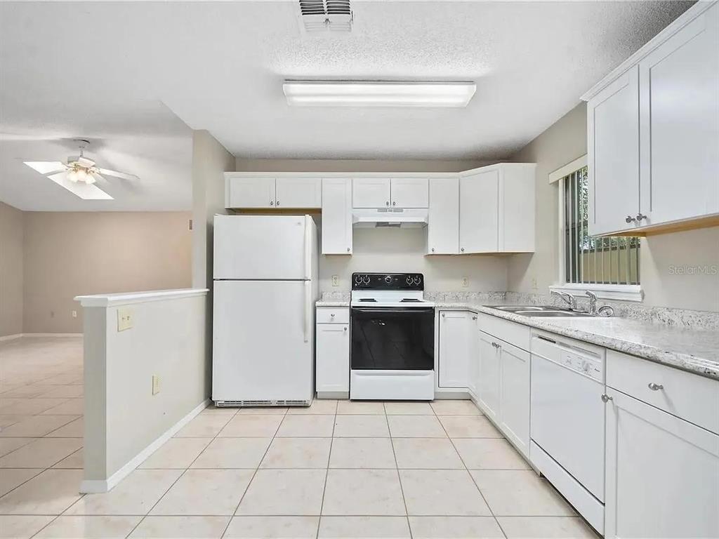 A kitchen with white cabinets, white appliances, and light-colored tile flooring — 1600 CIMARRON HILLS DRIVE, APOPKA, FL