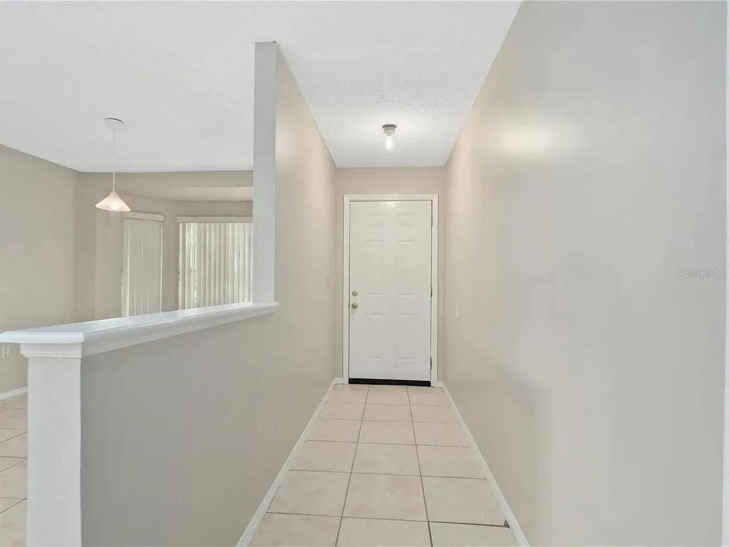 A tiled entryway leads to a white front door next to a half-wall partition — 1600 CIMARRON HILLS DRIVE, APOPKA, FL