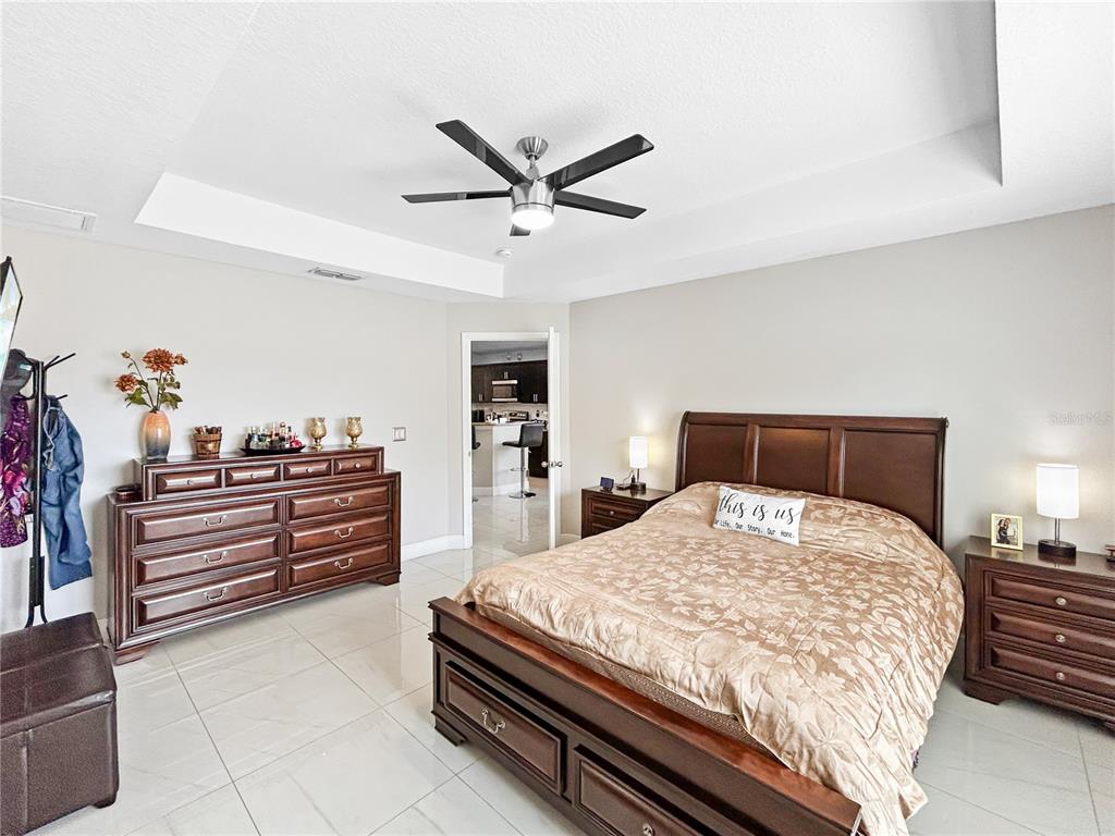 A bedroom features a dark wood bed frame, matching dressers, and light-colored tile flooring — 1017 FRASER PLACE, POINCIANA, FL