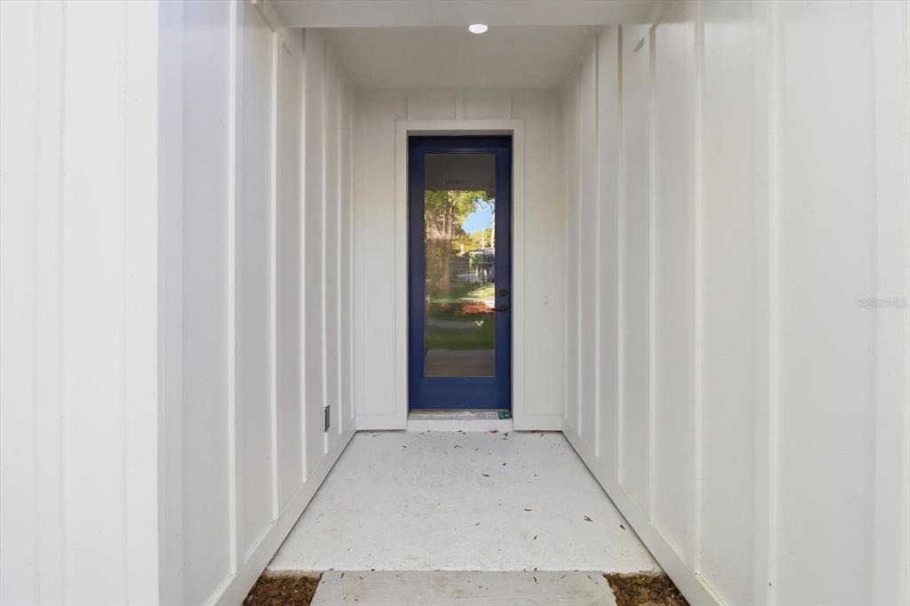 A covered entryway features white vertical siding walls and a blue glass-paneled front door — 19126 SW 101ST STREET, DUNNELLON, FL
