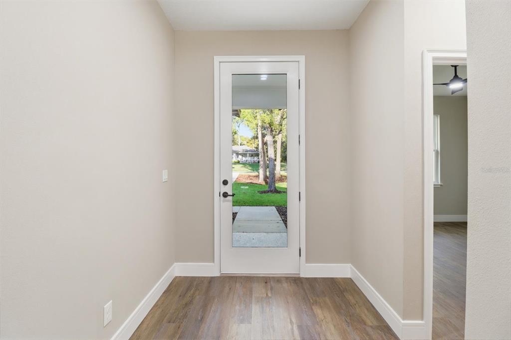 A hallway with wood-look flooring leads to an exterior door with a glass panel — 19126 SW 101ST STREET, DUNNELLON, FL
