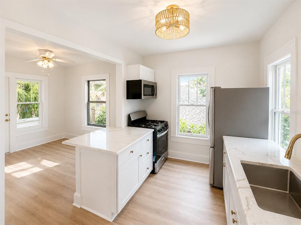 A kitchen features white cabinets, marble countertops, stainless steel appliances, and light wood-look flooring — 618 N 7TH AVENUE UNIT B, ST PETERSBURG, FL