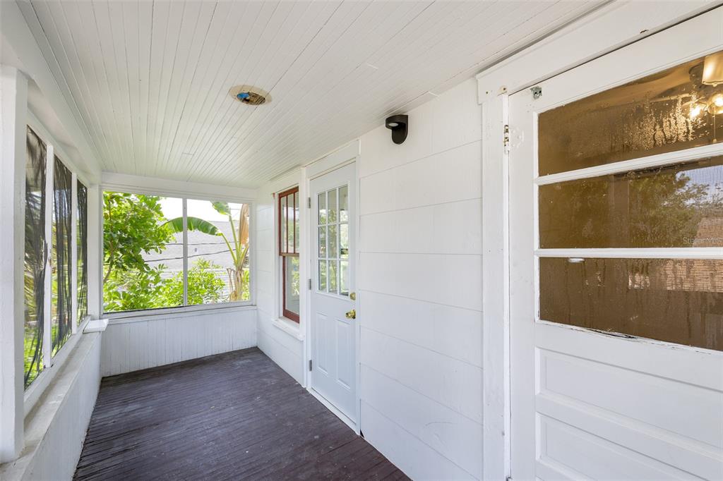 A white-walled enclosed porch features a wooden floor, large windows, and two white doors — 618 N 7TH AVENUE UNIT B, ST PETERSBURG, FL