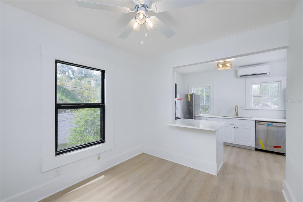 A dining area with light wood flooring opens into a white kitchen with a peninsula — 618 N 7TH AVENUE UNIT B, ST PETERSBURG, FL