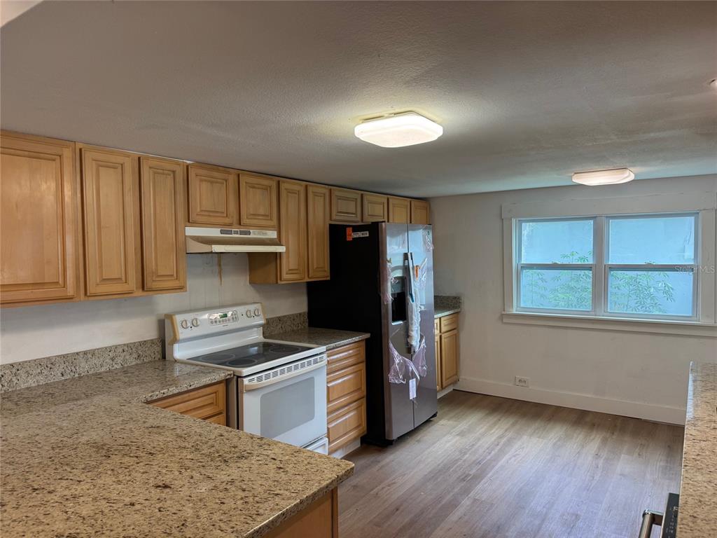 A kitchen features light wood cabinets, granite countertops, a white stove, and a stainless refrigerator — 2121 GREENWAY DRIVE, WINTER HAVEN, FL