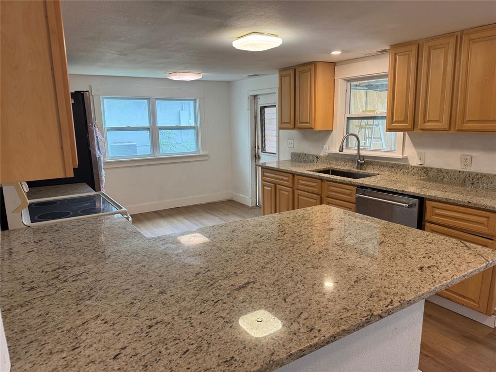 A kitchen features light wood cabinets, granite countertops, stainless steel appliances, and a dining area — 2121 GREENWAY DRIVE, WINTER HAVEN, FL