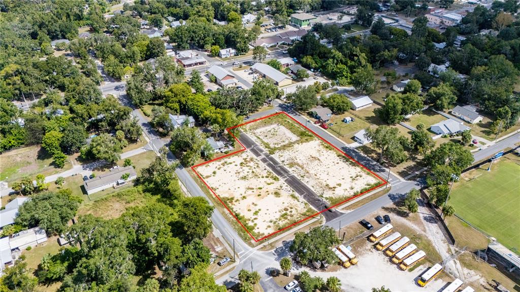 An aerial view shows a vacant, rectangular lot outlined in red near a school bus parking area — 000 SW 1ST STREET, NEWBERRY, FL