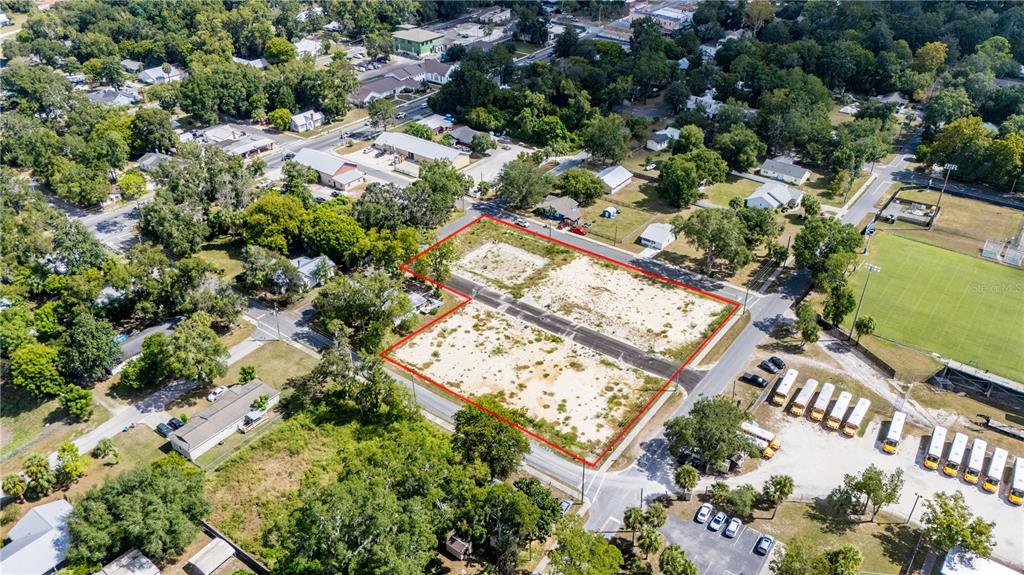 An aerial view shows a vacant, rectangular lot outlined in red near a school parking lot — 000 SW 1ST STREET, NEWBERRY, FL