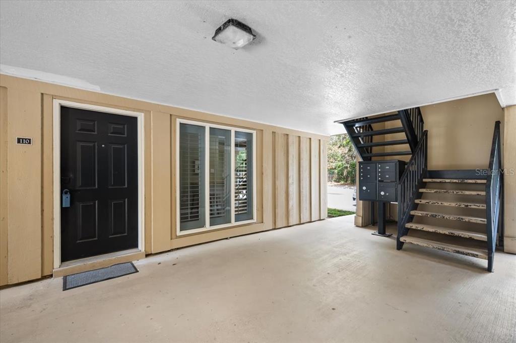 A covered entryway features a black front door, a window, and a staircase with mailboxes — 507 NW 39TH ROAD UNIT 110, GAINESVILLE, FL