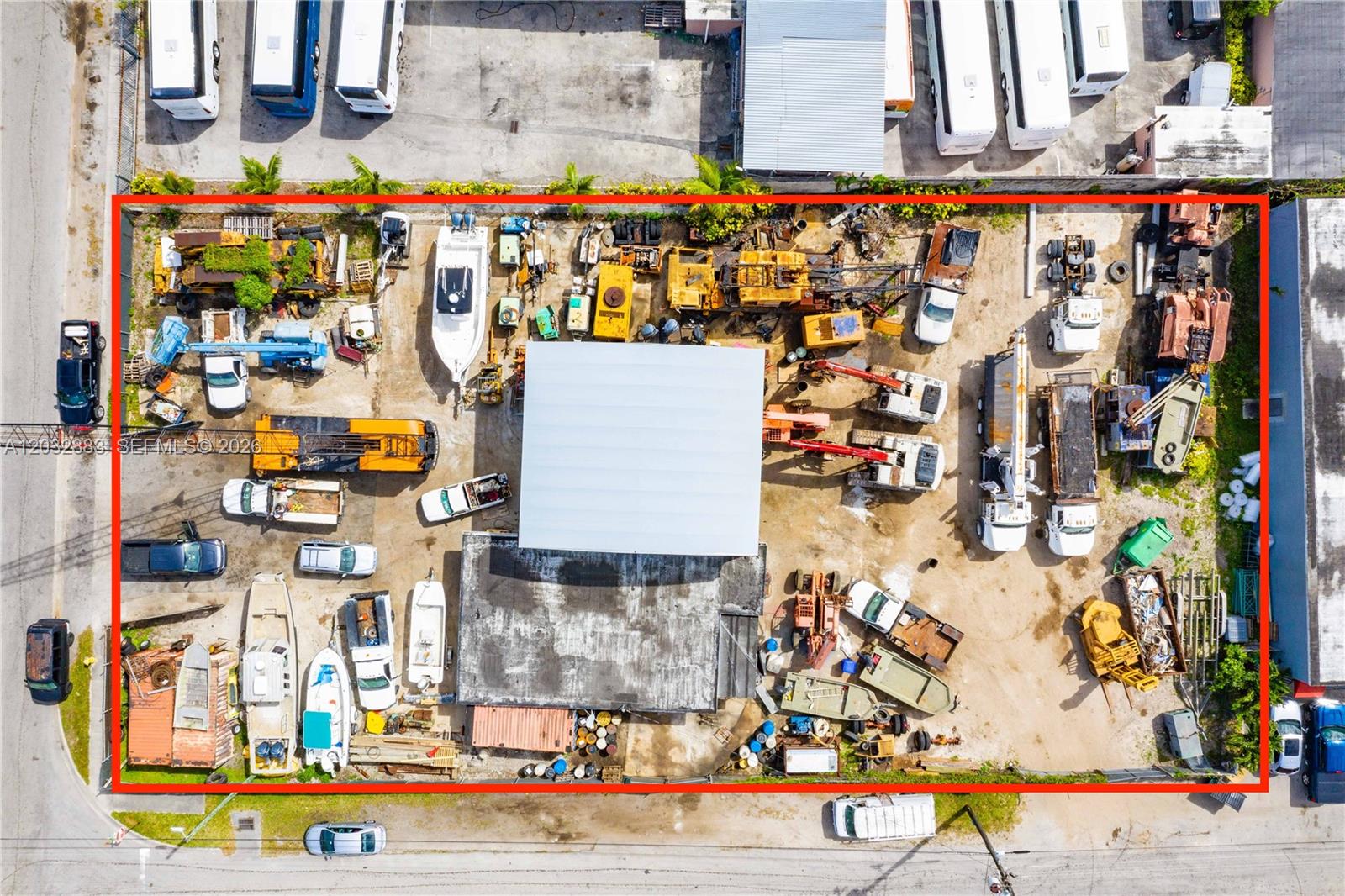 An aerial view shows a fenced industrial lot filled with construction equipment, vehicles, and boats — 2301 SW 57th Ave, West Park FL 33023, WEST PARK, FL