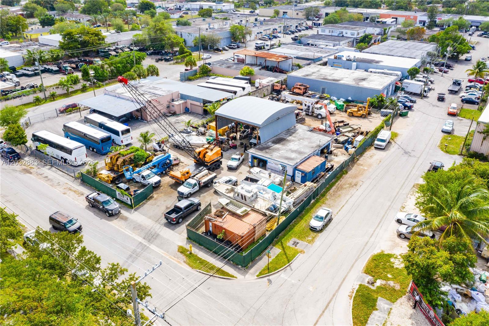 An aerial view shows a commercial property with a crane, buses, and various work vehicles — 2301 SW 57th Ave, West Park FL 33023, WEST PARK, FL