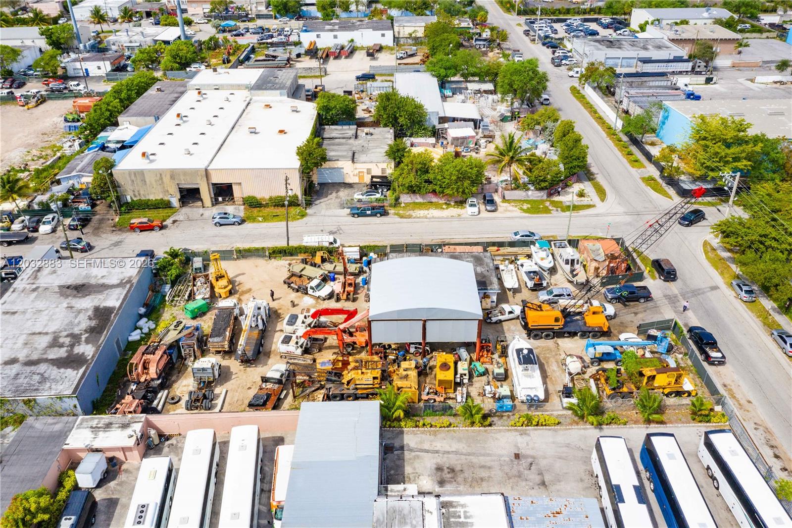 An aerial view shows a commercial lot filled with construction equipment, boats, and parked buses — 2301 SW 57th Ave, West Park FL 33023, WEST PARK, FL