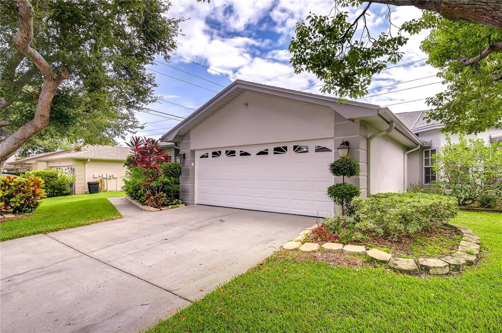 A single-story house with a white garage door, concrete driveway, and landscaped front yard — 2999 BROOKFIELD LANE, CLEARWATER, FL
