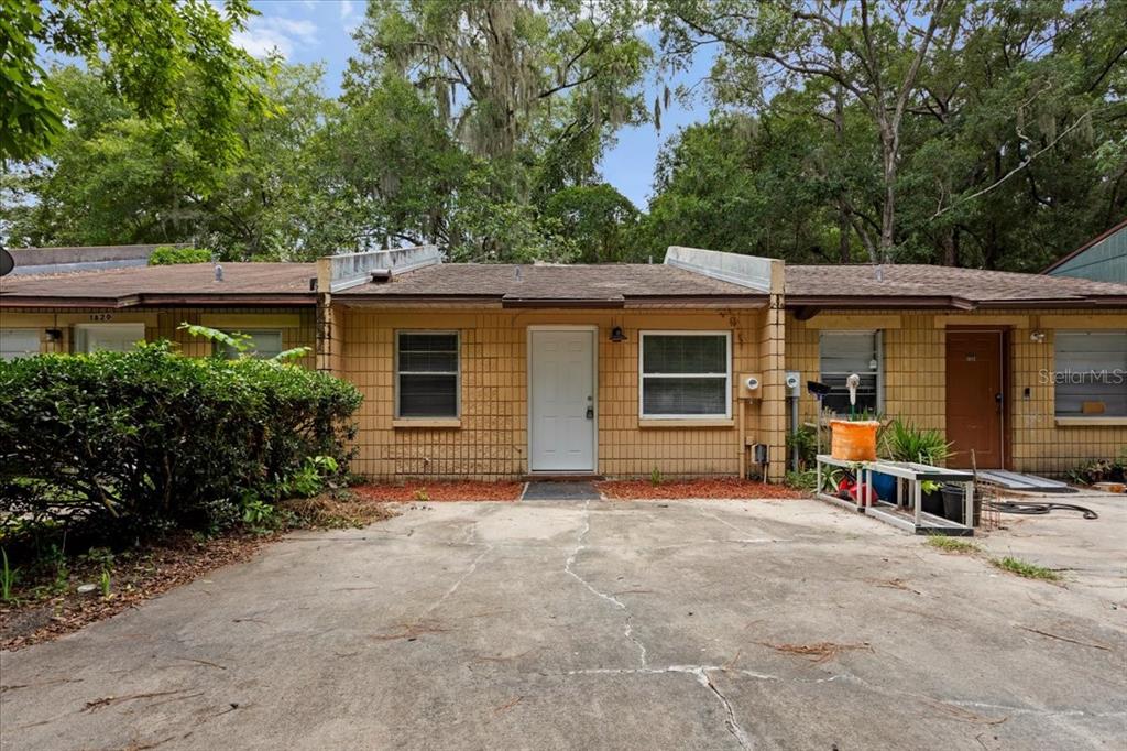A single-story brick townhouse exterior features a concrete driveway, a white front door, and windows — 1816 SW 70TH TERRACE, GAINESVILLE, FL