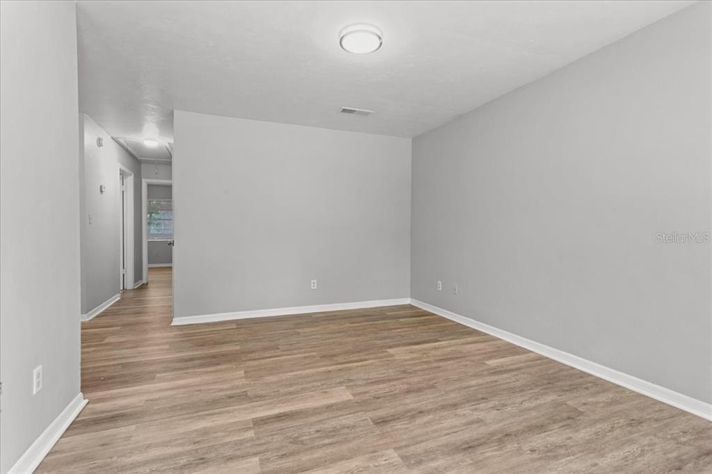 An empty room with light gray walls, wood-look flooring, and a central ceiling light — 1816 SW 70TH TERRACE, GAINESVILLE, FL