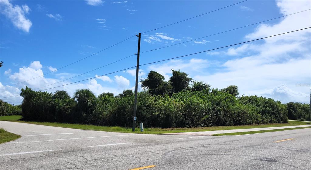 A vacant, overgrown corner lot sits at the intersection of two paved roads — 10044 CALUMET BOULEVARD, PORT CHARLOTTE, FL