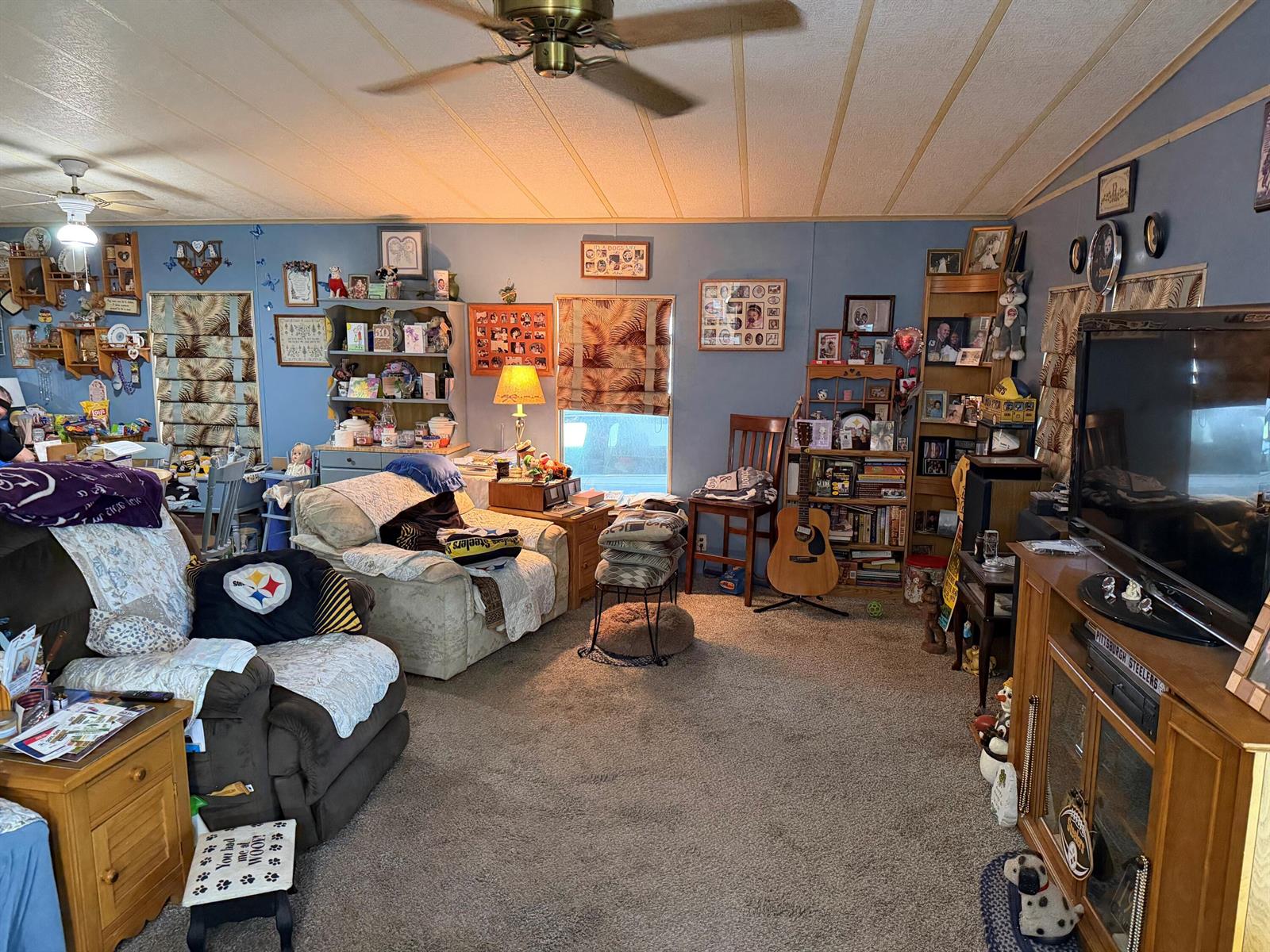 A living room with blue walls, carpeted flooring, a ceiling fan, and various personal decor items — 5230 SW 29th Terrace, Dania Beach FL 33312, DANIA BEACH, FL