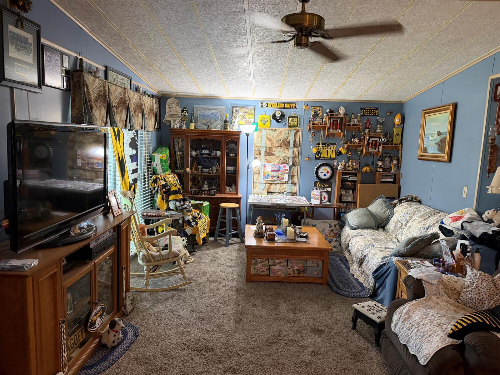 A living room features blue walls, carpeted flooring, a ceiling fan, and Pittsburgh Steelers decor — 5230 SW 29th Terrace, Dania Beach FL 33312, DANIA BEACH, FL