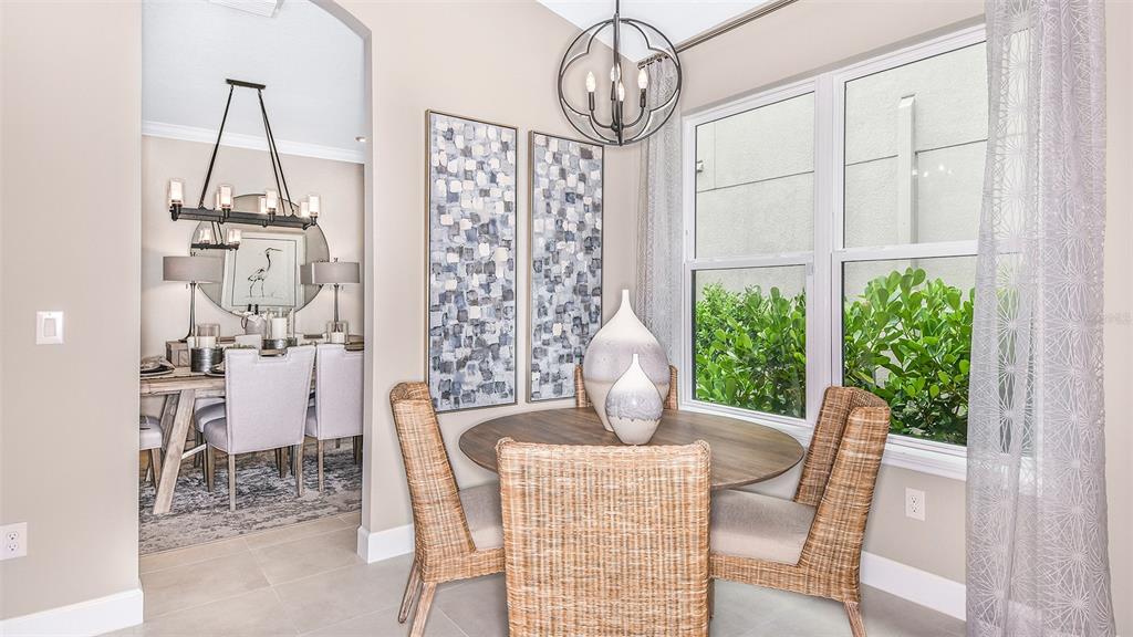 A dining nook with a round wooden table and wicker chairs sits beside a formal dining room — 8220 SUMMER NIGHT ROAD, SARASOTA, FL