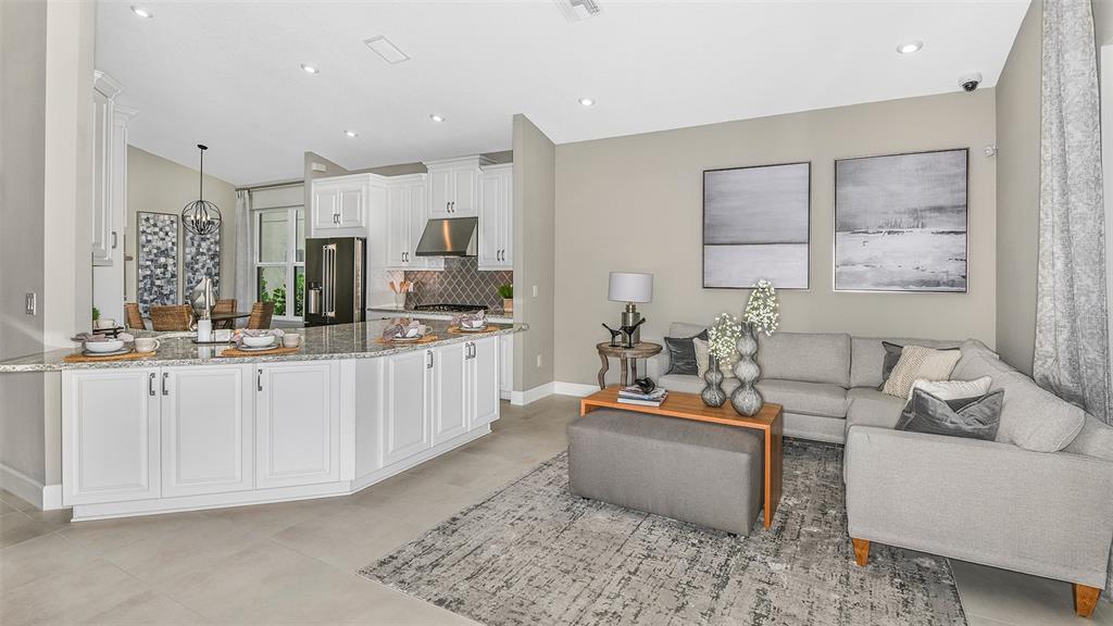 A modern open-concept kitchen with white cabinetry and granite countertops flows into a living area — 8220 SUMMER NIGHT ROAD, SARASOTA, FL