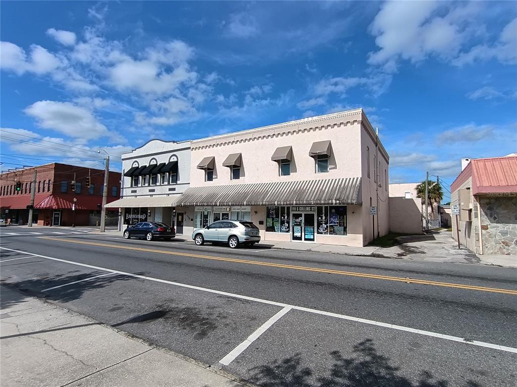 A two-story commercial building with a light-colored facade sits along a street — 111 S COLLINS STREET, PLANT CITY, FL