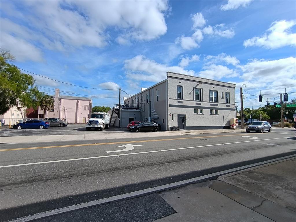 A two-story grey commercial building stands next to a parking lot under a blue sky — 111 S COLLINS STREET, PLANT CITY, FL