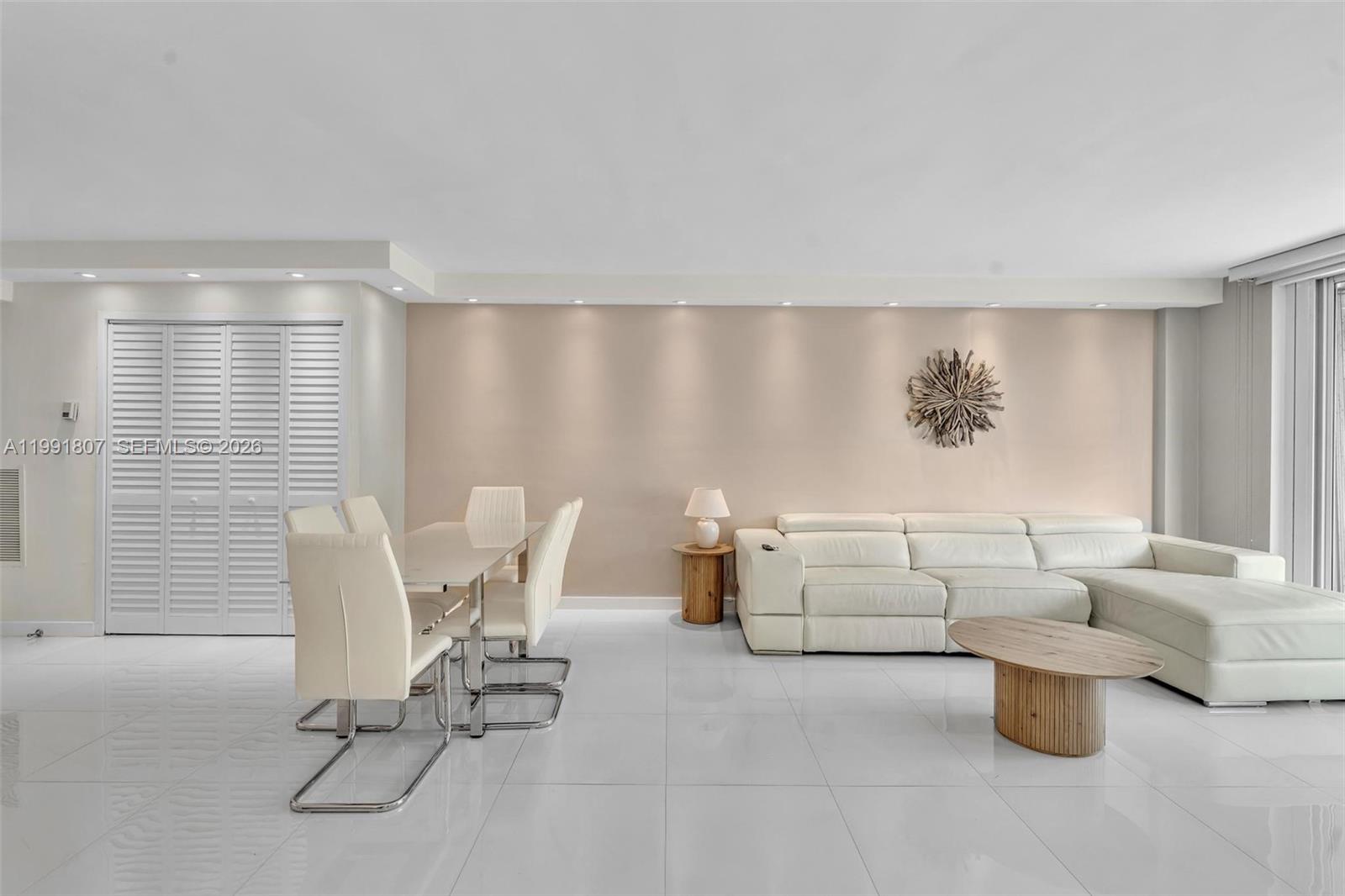 A bright living and dining area features white tile floors, a sectional sofa, and recessed lighting — 9195 Collins Ave # 303, Surfside FL 33154, SURFSIDE, FL