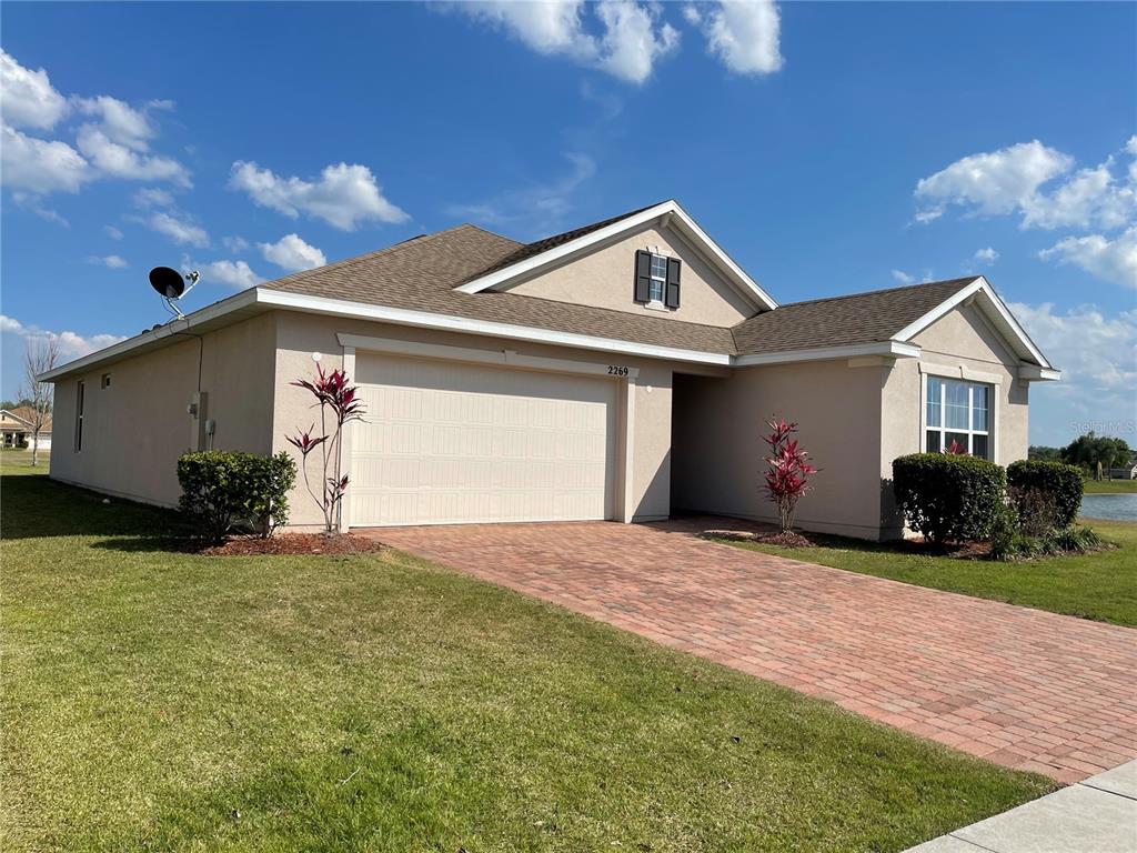 A tan, single-story house with a brick paver driveway and a two-car garage — 2269 WAUKEGAN DRIVE, KISSIMMEE, FL
