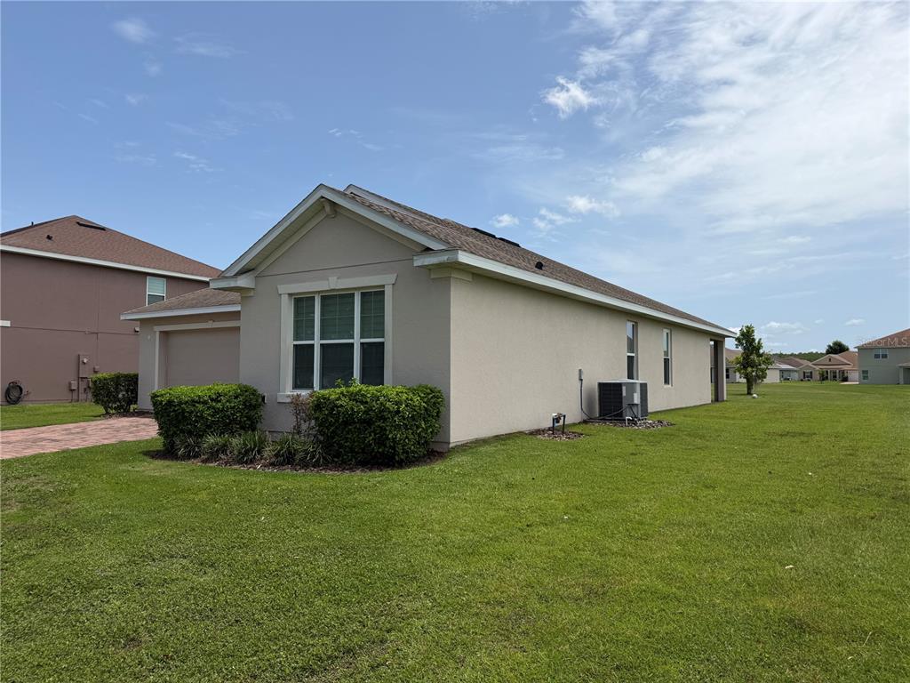 A side view of a beige single-story house with a garage and green lawn — 2269 WAUKEGAN DRIVE, KISSIMMEE, FL