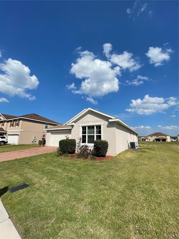 A single-story beige house with a two-car garage sits on a grassy lot — 2269 WAUKEGAN DRIVE, KISSIMMEE, FL