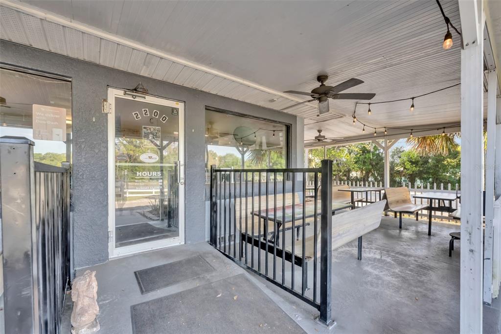 A covered outdoor patio features a black metal fence, wooden benches, and a ceiling fan — 2200 N VOLUSIA AVENUE, ORANGE CITY, FL