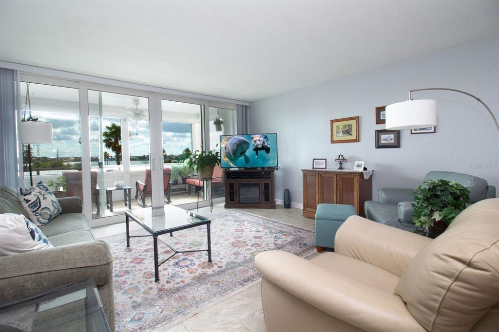 A living room with a glass coffee table, area rug, and sliding doors to a balcony — 17920 GULF BOULEVARD UNIT 301, REDINGTON SHORES, FL