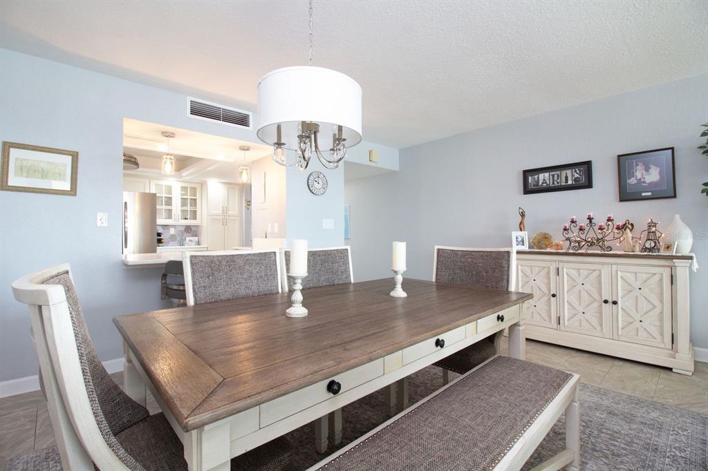 A dining room features a wooden table, upholstered chairs, a bench, and a white sideboard — 17920 GULF BOULEVARD UNIT 301, REDINGTON SHORES, FL