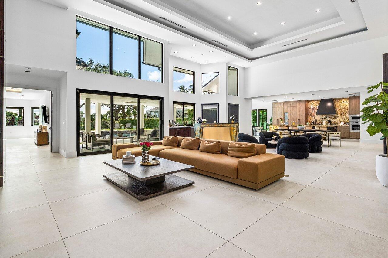 A spacious, modern living room with high ceilings, a tan sectional, and large glass doors — 4825 Bocaire Boulevard, Boca Raton FL 33487, BOCA RATON, FL