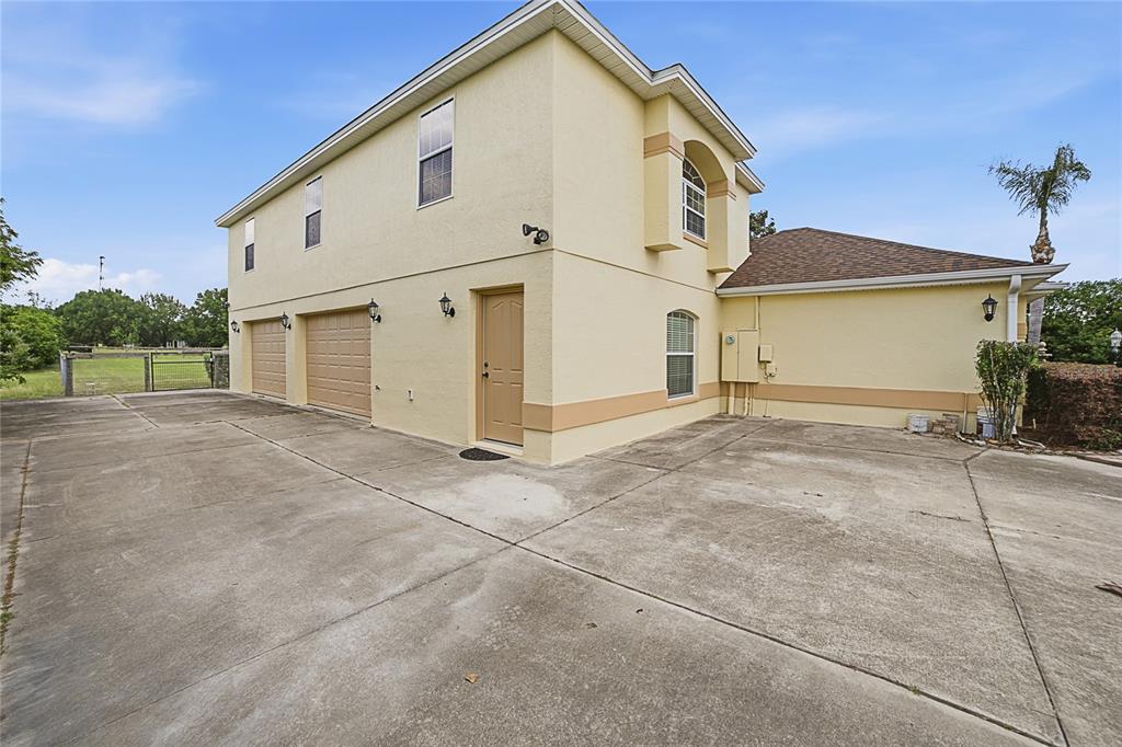 A two-story house with a beige stucco exterior, two garage doors, and a concrete driveway — 4141 COUNTY ROAD 121D, WILDWOOD, FL