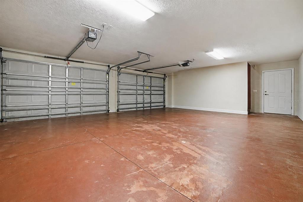 An empty two-car garage with a stained concrete floor, white walls, and two overhead doors — 4141 COUNTY ROAD 121D, WILDWOOD, FL