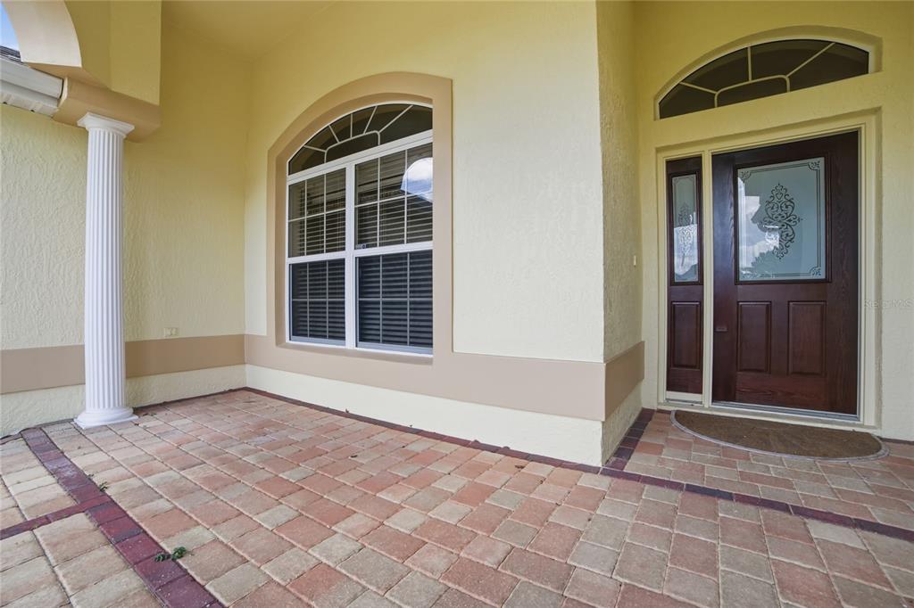 A paved front porch features a white column, a large arched window, and a dark wood door — 4141 COUNTY ROAD 121D, WILDWOOD, FL