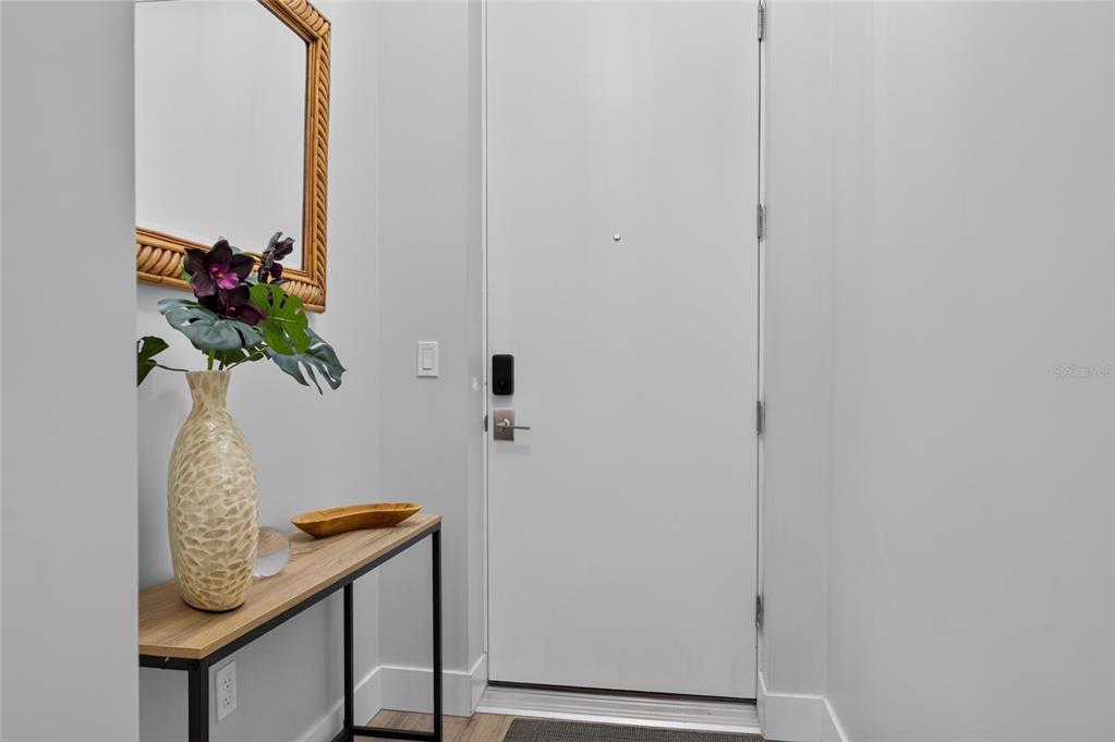 An entryway features a console table, a decorative vase, a mirror, and a white door — 1709 N TAMIAMI TRAIL UNIT 505, SARASOTA, FL