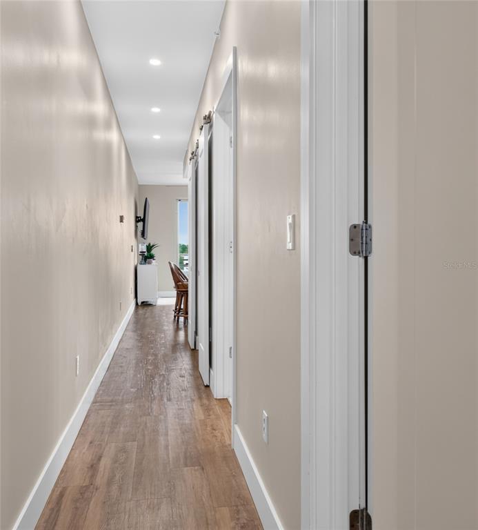 A long hallway with light-colored walls, wood-look flooring, and recessed ceiling lighting — 1709 N TAMIAMI TRAIL UNIT 505, SARASOTA, FL